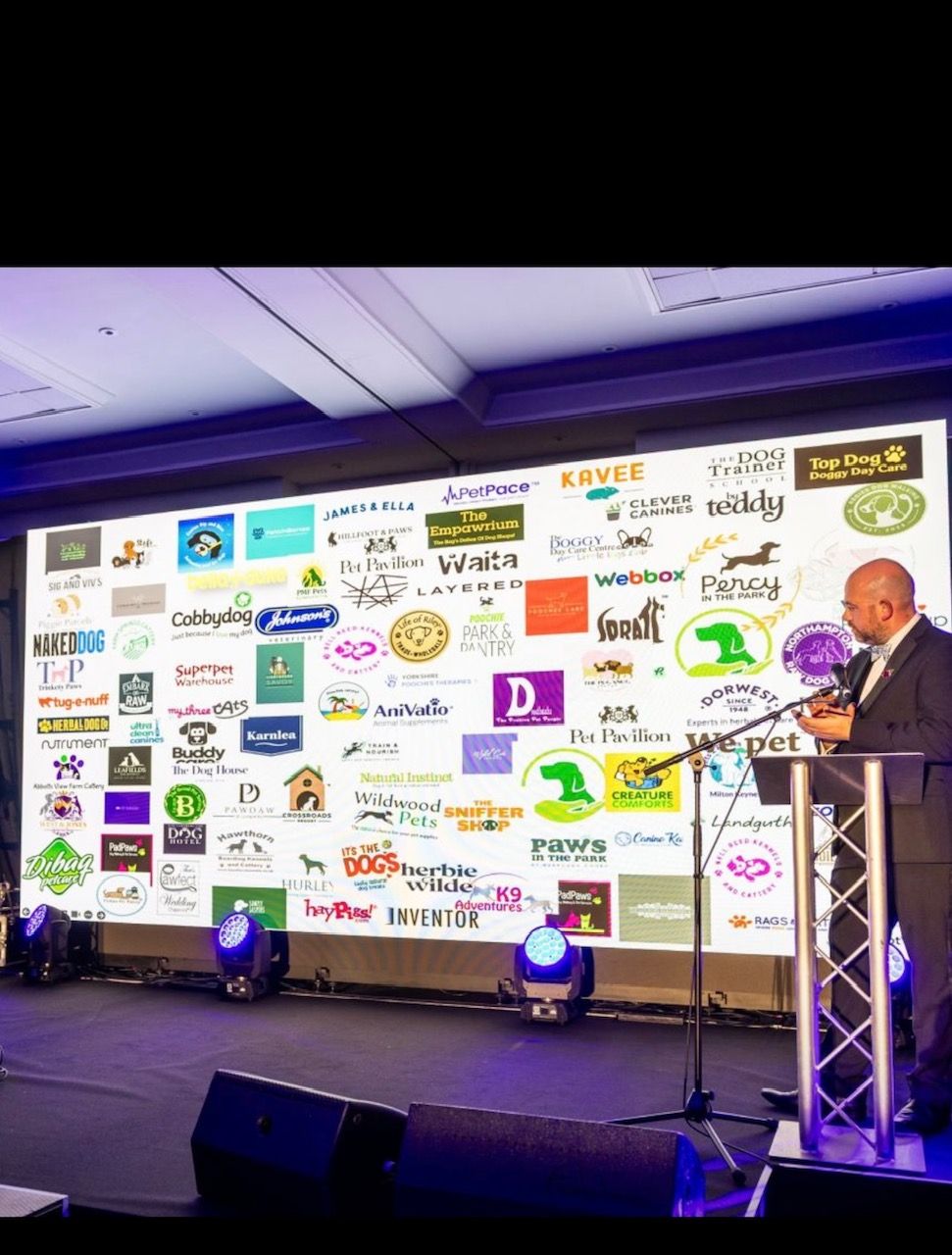 The Pet Industry Federation Awards finalists board on stage, with the AniVatio logo among dozens of pet industry brands